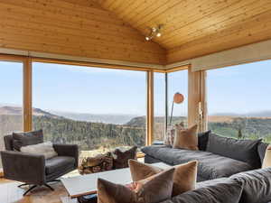 Sunroom / solarium featuring a wooded view, healthy amount of natural light, lofted ceiling, a mountain view, and wooden ceiling