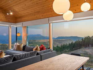 Living room featuring a mountain view, wood ceiling, vaulted ceiling, and a view of trees