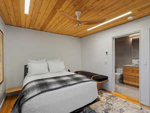 Bedroom with light wood finished floors, wood ceiling, and ensuite bath