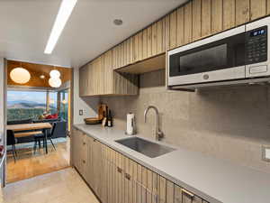 Kitchen with stainless steel microwave, light countertops, tasteful backsplash, a mountain view, and light tile patterned flooring