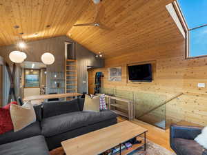 Living room featuring wood finished floors, high vaulted ceiling, wood walls, a skylight, and wood ceiling