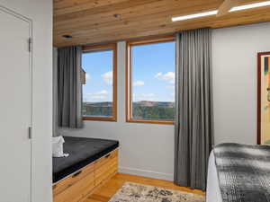 Bedroom with light wood finished floors, wooden ceiling, and a mountain view
