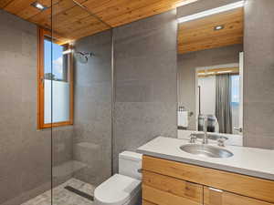 Full bath featuring walk in shower, wooden ceiling, vanity, and tile walls