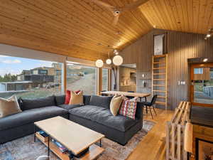 Living room with plenty of natural light, wood finished floors, wooden walls, high vaulted ceiling, and wooden ceiling