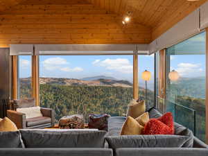 Sunroom with a mountain view, a wooded view, and lofted ceiling