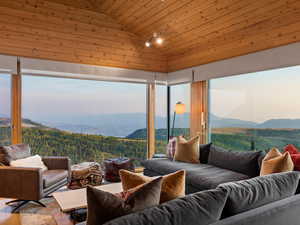 Living area with wood ceiling, vaulted ceiling, a mountain view, a wooded view, and wood finished floors