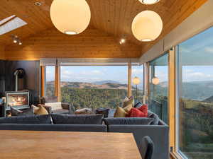 Living area featuring a wood stove, a mountain view, wood ceiling, vaulted ceiling, and a skylight