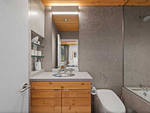 Full bathroom with tile walls, a bath, and vanity