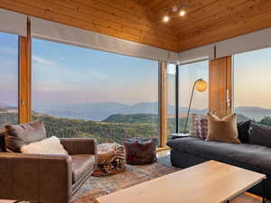 Living area featuring a mountain view, lofted ceiling, rail lighting, healthy amount of natural light, and wooden ceiling