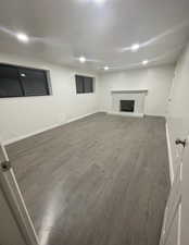 Basement featuring dark wood-style flooring and a fireplace with raised hearth