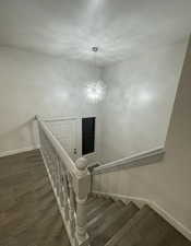 Stairs with a chandelier and wood finished floors