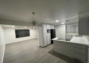 Kitchen with a peninsula, light wood-type flooring, recessed lighting, light countertops, and black electric stovetop