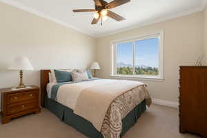 2nd bedroom featuring crown molding, light colored carpet, ceiling fan, mirrored wardrobe sliding doors and a mountain view
