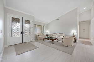 Main Entry / Living room featuring ornamental molding, french leaded-glass entry doors, high vaulted ceiling, and 3-tone paint, tile & carpet flooring
