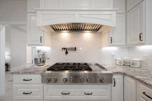 Main Kitchen featuring tile backsplash, stainless steel gas 48" cook-top, custom exhaust hood, and white soft-close cabinets