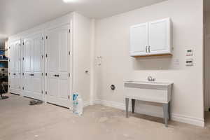 Garage featuring a washtub, indoor nozzle & cabinetry for water heaters & A/C.