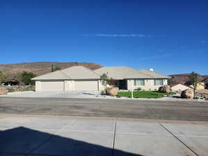 Ranch-style home featuring concrete driveway, a mountain view, a garage, a front yard, and a chimney
