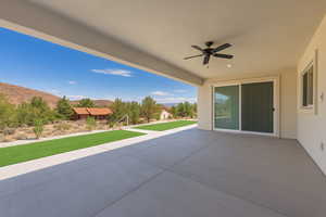 View of rear covered patio / terrace featuring a mountain view and ceiling fan.Concrete sidewalks surround the home.