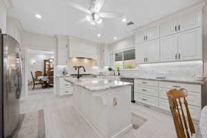 Main Gourmet Kitchen with white tile backsplash, stainless steel appliances, white soft-close cabinets, ceiling fan, granite countertops and recessed lighting with tile flooring