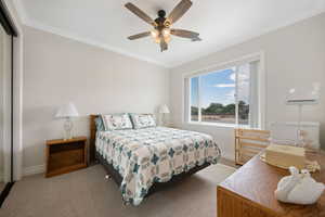 ADU carpeted bedroom featuring crown molding, ceiling fan, and a full length mirrored wardrobe closet