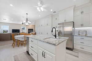 Main Gourmet Kitchen with a ceiling fan, stainless steel fridge, an island with sink, granite stone countertops, and recessed lighting plus nook with overhead fixture and family room with floor to ceiling stone fireplace with hearth.