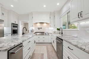 Main Gourmet Kitchen with white soft-close  cabinets, recessed lighting, appliances with stainless steel finishes, granite stone countertops, and decorative tile backsplash