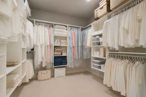 Master Suite first spacious closet with light carpet, lot of shelving and space.