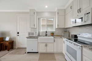 ADU Kitchen with white appliances, soft-close cabinetry, tasteful tile backsplash, crown molding, granite stone countertops and tile flooring