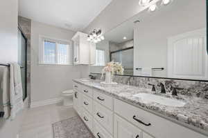 ADU Bathroom featuring double vanity and toilet, soft-close cabinetry, tile flooring, granite countertops, tile shower with sliding door.