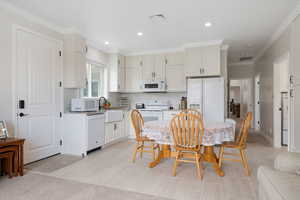 ADU Kitchen with ornamental molding, decorative tile backsplash, granite countertops, white appliances, recessed lighting, soft-close cabinetry and tile flooring.