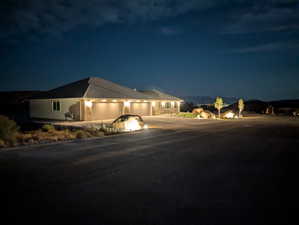 Single story home with a 5+ garage showing two 18' doors, concrete driveway and exterior night lighting