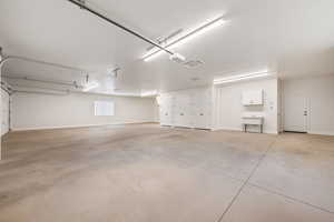 Air-cooled garage with baseboards, widows with vertical blinds, cabinetry for water heaters, A/C and attached air-cooled pantry storage room.