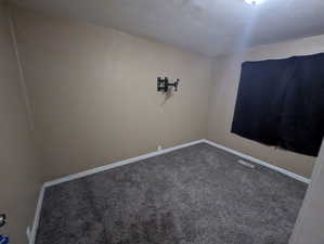 Empty room featuring dark colored carpet and baseboards