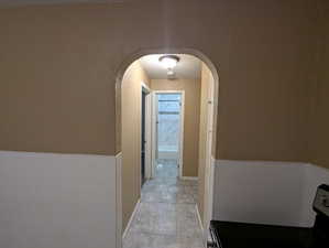 Corridor featuring arched walkways and light tile patterned floors