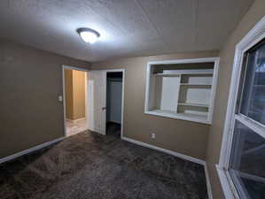 Unfurnished bedroom featuring carpet flooring, a textured ceiling, and a closet