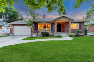 Ranch-style house featuring brick siding, an attached garage, concrete driveway, a yard, and roof with shingles