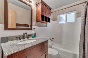 Full bathroom featuring shower / bathtub combination with curtain, vanity, and tile walls
