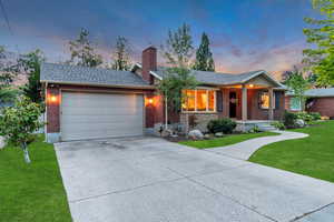 Single story home featuring a front yard, an attached garage, brick siding, and a chimney
