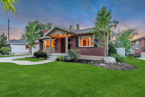 Ranch-style house with a front yard, a chimney, brick siding, a garage, and concrete driveway