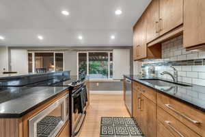Kitchen with appliances with stainless steel finishes, recessed lighting, brown cabinetry, tasteful backsplash, and light wood finished floors