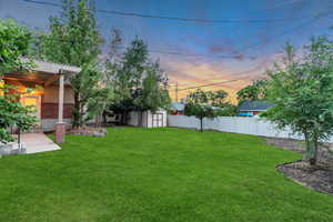 Yard at dusk featuring a storage unit and a fenced backyard