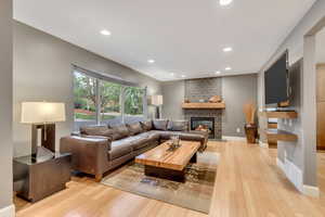 Living room with recessed lighting, light wood-type flooring, and a fireplace
