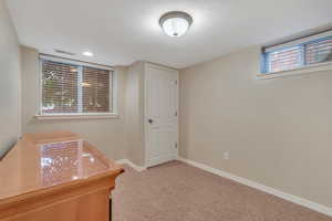 Carpeted office featuring baseboards and a textured ceiling