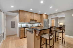 Kitchen featuring backsplash, stainless steel appliances, recessed lighting, a breakfast bar area, and light wood-type flooring