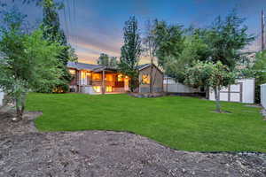 Back of house at dusk with a storage unit