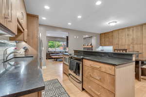 Kitchen featuring appliances with stainless steel finishes, dark stone countertops, recessed lighting, light wood-type flooring, and decorative backsplash