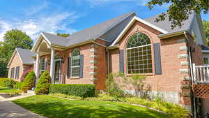 View of front facade with brick siding, a front lawn, and a shingled roof