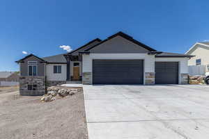 Craftsman-style home with stone siding, an attached garage, and concrete driveway