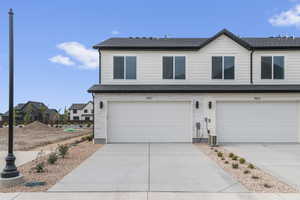 View of front of home with driveway, a garage, a shingled roof, and a residential view