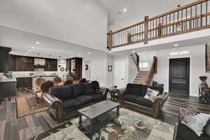 Living room with recessed lighting, a towering ceiling, dark wood-style floors, and stairs